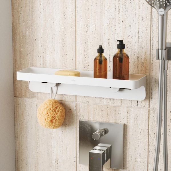 Een wit modern doucherek met badproducten aan een beige wand.